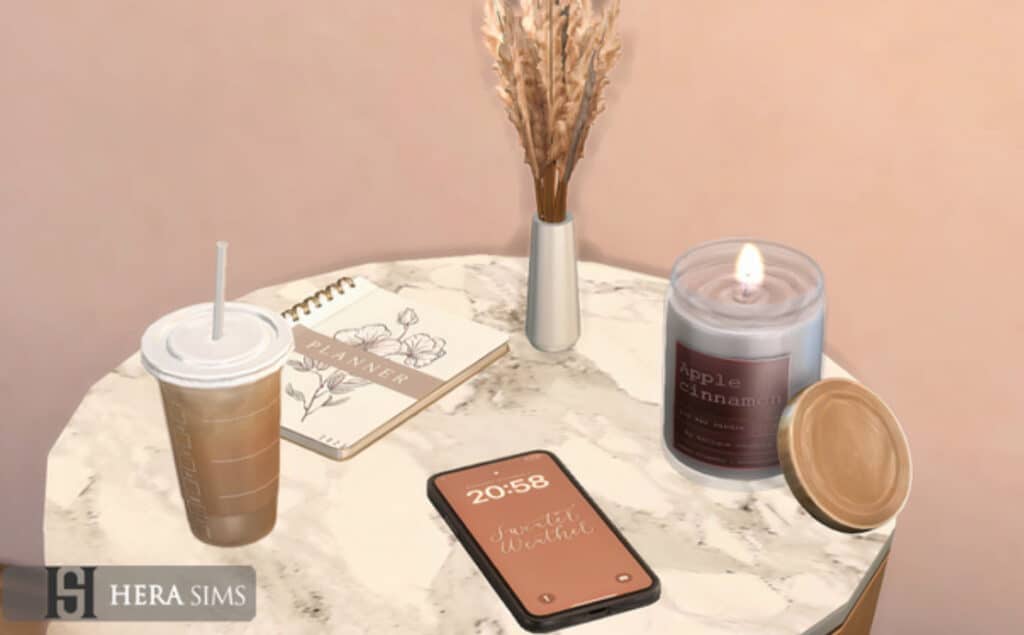 Coffee cup with straw, planner notebook, smartphone displaying time, scented candle, and vase with dried flowers on a marble table, showcasing popular Must Have Mods accessories and decor for Sims 4.